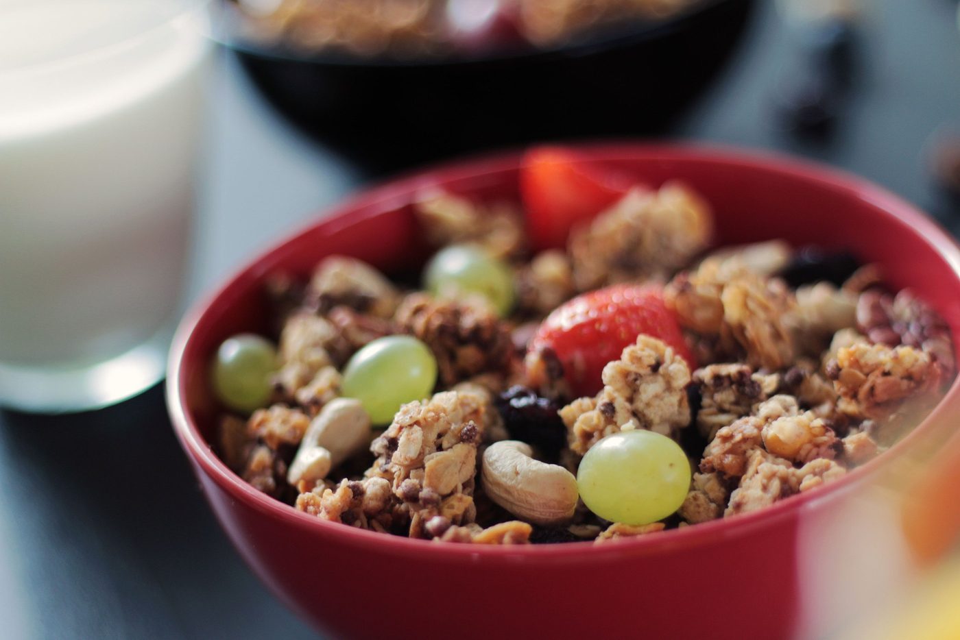 Müsli mit Trauben, Erdbeeren und Cashews in einer roten Schale
